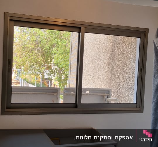 חלון הזזה מאלומיניום מותקן בקיר בחדר בתהליך שיפוץ